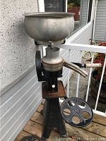 Full view of vintage creamer machine showing large basin on top, spigot, cast iron base and gear wheel.