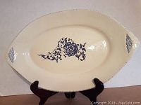 Oval porcelain tray with central and end blue floral pattern, displayed on stand.