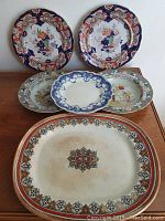 Full set of six plates and bowls arranged on a wooden surface, showing various sizes and designs