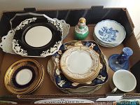 Assorted vintage plates, bowl, teacup, porcelain bottle, and blue and white candlestick in a box, showing various patterns and some wear.