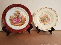 Photo showing both decorative plates on stands, front view, highlighting designs and condition