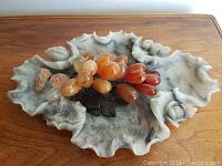 Soapstone bowl with carved floral and leaf accents, showing the full bowl and grape cluster placed inside.