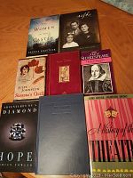 Overview of all eight books laid out on a wooden surface showing varying sizes and cover designs for identification and condition assessment.