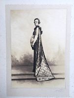 Full view of original framed photograph depicting a woman in an elaborate Art Deco gown with a long cape and gloves, standing in profile.