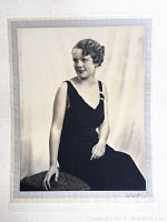 Full view of the large black and white portrait photograph showing a seated woman in a dark dress.