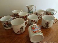 Set of 9 antique German porcelain children's nursery rhyme mugs on wooden surface