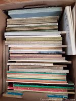 Top view of a box filled with stacked Sotheby's auction catalogues, showing various titles and years
