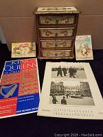 Photo showing musical jewelry box, 2 vintage postcards, 1953 Queen Elizabeth calendar page, and Kings and Queens history chart booklet