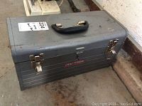 Closed gray metal Craftsman toolbox with black handle and metal latches