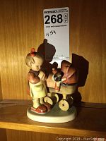 Front view of the figurine showing the girl looking at the doll stroller with the doll inside.