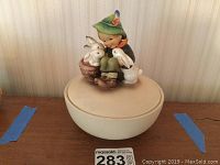 Full view of the round box with the boy and bunnies figurine lid on top, showing size and proportion.