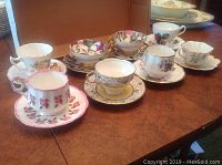 Full view of 8 assorted tea cups and saucers with varied floral patterns, showing overall condition and designs