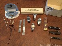 Full lot on table showing Bulova box, Benrus box, watch parts, bands, watches and knives