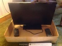 Photo of 19 inch Insignia TV with remote and power adapter in cardboard box