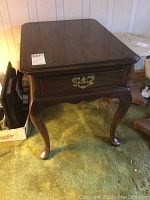 Front angle view of the Harden end table showing the wood finish, cabriole legs, and brass hardware on the drawer.