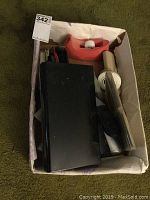Box containing assorted desk supplies - black box, tape dispenser, paper roll