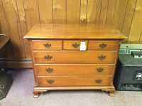 Front view of the wooden dresser showing all five drawers closed and the brass handles.