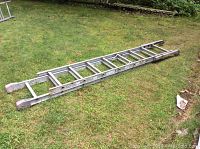 Full length view of the 13 foot aluminum ladder laid out on grass, showing ladder structure and size.