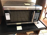 Full view of Cuisinart microwave oven on a black surface showing front panel, digital display, keypad, and handle.