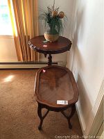 Two antique wooden side tables positioned in corner; one oval with glass top and one pie crust round table, showing overall condition and scale.