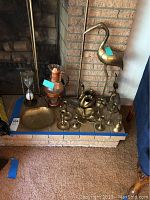 Photo showing the entire collection arranged on the hearth including the large brass crane statue, copper coffee carafe, candle holders, and other brass decorative items.