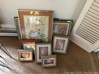 Group photo of various framed wall art and shell displays on carpeted floor showing layouts and sizes.