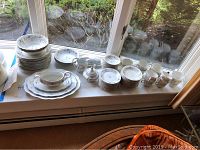 Full set of Johann Haviland china laid out on windowsill showing various sizes of plates, cups, bowls, and serving pieces.