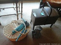 Lot contents showing wooden sewing box, wicker basket with wind chime, and metal yard decor figurine