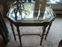 Front view of octagonal wooden side table with glass top, showing turned legs and overall condition.