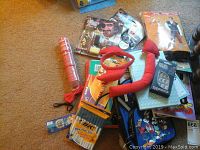 Overall lot showing various children's toys, costume items, and activity books clustered on carpeted floor.
