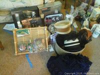 Overview of makeup, bath items, and vintage hats, piled on carpet with storage basket and small items visible