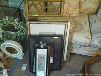Grouped view showing all art pieces and mirrors stacked on the floor in front of a couch and chair.
