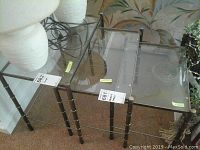 Top angled view of the three nesting glass tables stacked one inside the other showing glass tops and metal legs.