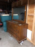 Front view of wooden dresser with nine drawers and attached mirror showing front design and condition.