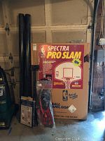 Photo of NBA Spectra Pro Slam basketball hoop box and black poles, with additional equipment in front