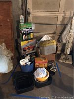 Overview of all items in the lot arranged on floor including ArmorAll gift packs, plastic containers and white coiled cord.