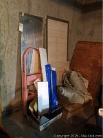 Wide view of the collection showing the folding pink stepladder, full-length mirror, various wood boards, fabric drop cloths, blue and white packaging, and cardboard boxes.