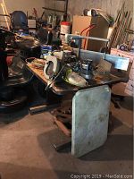 Photo showing disassembled antique marble table parts including chipped marble top and assorted tools on an adjustable work table. Visible is the marble top leaning.