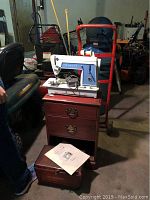 Vintage Singer Model 604 Touch & Sew sewing machine on a wooden nightstand with sewing box and some documents on top