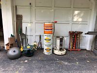 Wide shot of the lot showing gardening tools, wooden birdhouses, vintage kerosene cans stacked, portable heater, and croquet set in wooden rack.