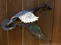 Close image of two metal ducks mounted on a fence in flying position with textured metal wings and body.
