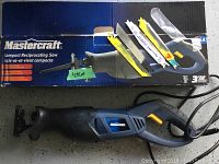 Mastercraft reciprocating saw lying on floor in front of box with blades taped to box.