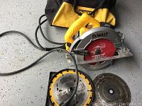 Full kit photo showing the DeWalt circular saw, two blades, and carrying case all placed on a concrete surface.