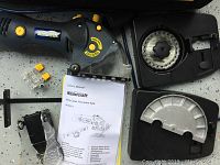 Full view of Mastercraft multi-cutter precision saw, blade guard, small yellow parts, black attachment, and owner's manual inside hard plastic case.