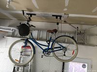 Front and side view of the step-through frame bike showing blue and cream steel frame, brown saddle, white tires and black woven basket