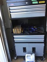 Full view of Stanley tool chest with top and bottom units, open center shelf showing wood blocks, clamps and plastic jug