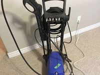Front view of blue Simoniz electric pressure washer including black hose, gun, and handle.