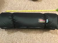 Rolled black Therm-a-Rest camping mattress with measuring tape showing approximate rolled length.