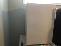 Side view of white upright freezer showing smooth finish and corner placement.