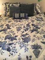 Queen bed made with floral comforter and three throw pillows
